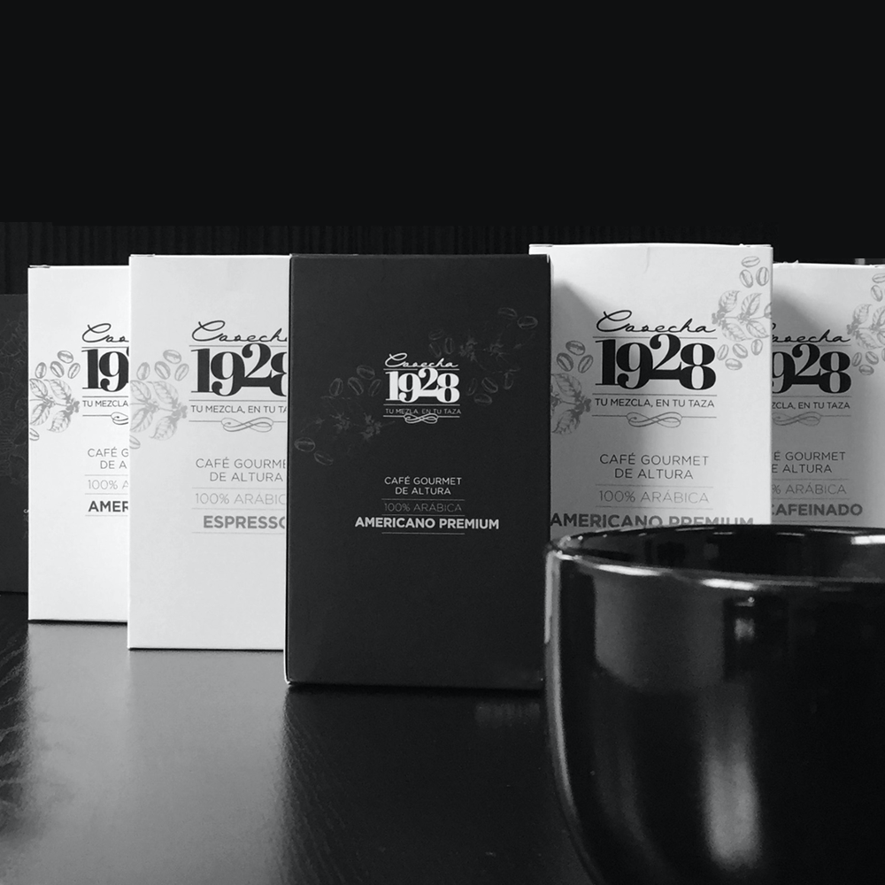 Hilera de paquetes blancos y negros de café Cosecha 1928 junto a una taza negra