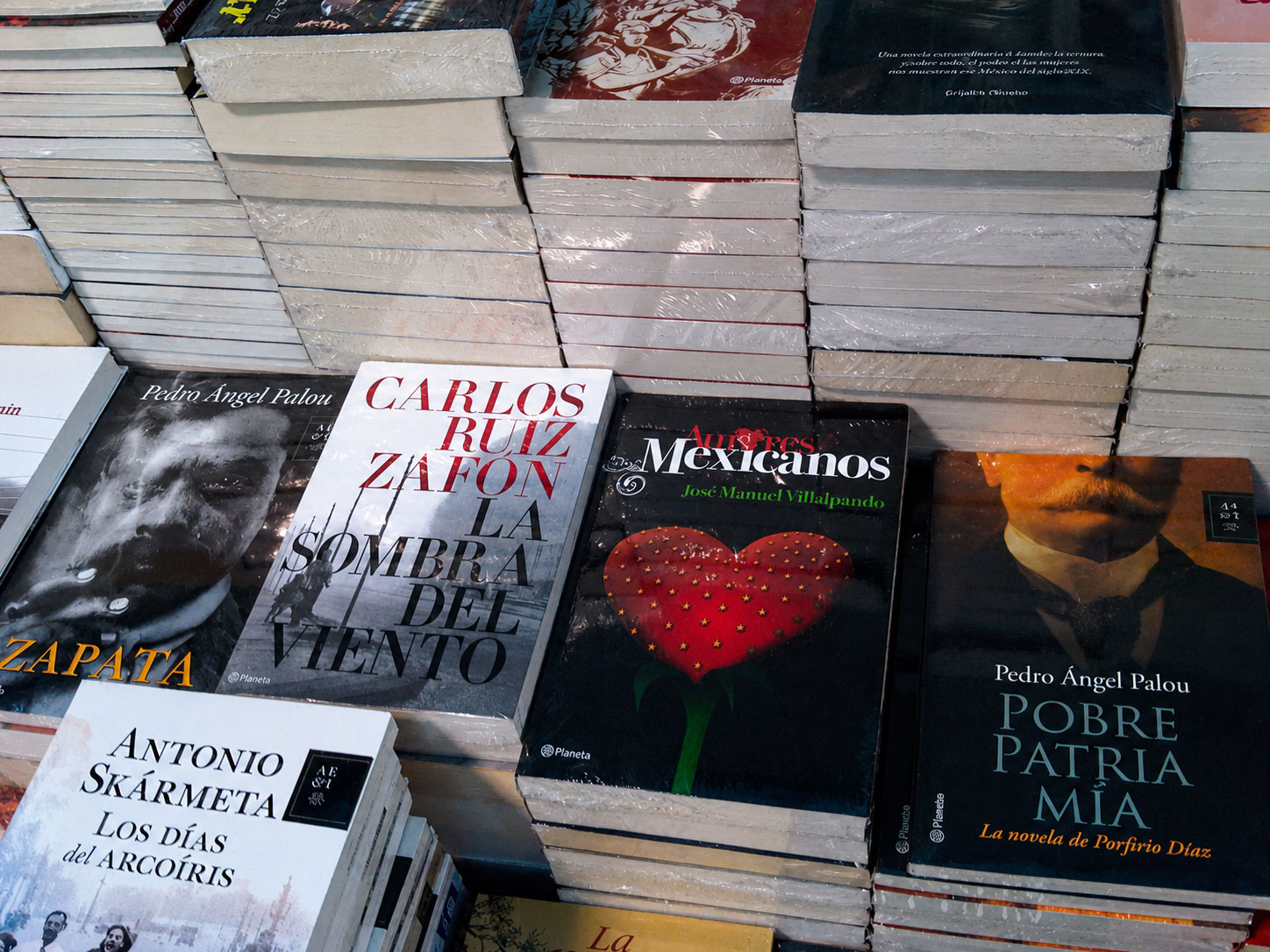 Pila de libros sobre una mesa, con la novela Amores Mexicanos entre otros títulos
