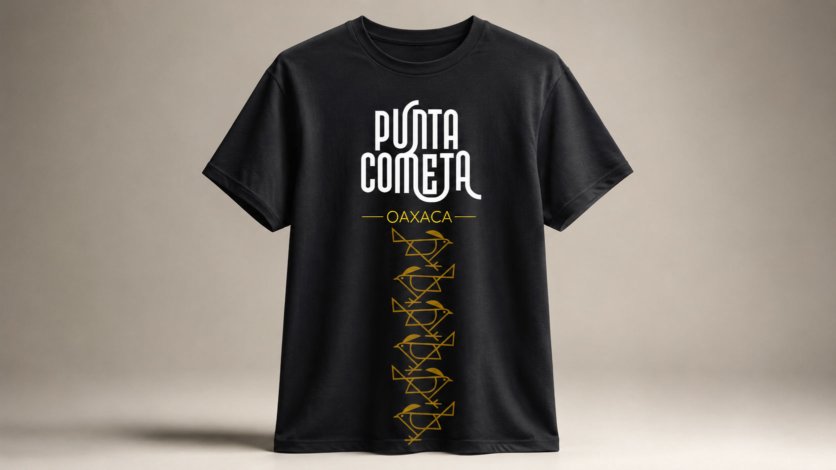 Playera negra con el logotipo de Punta Cometa Oaxaca y un patrón dorado de urracas a lo largo del frente