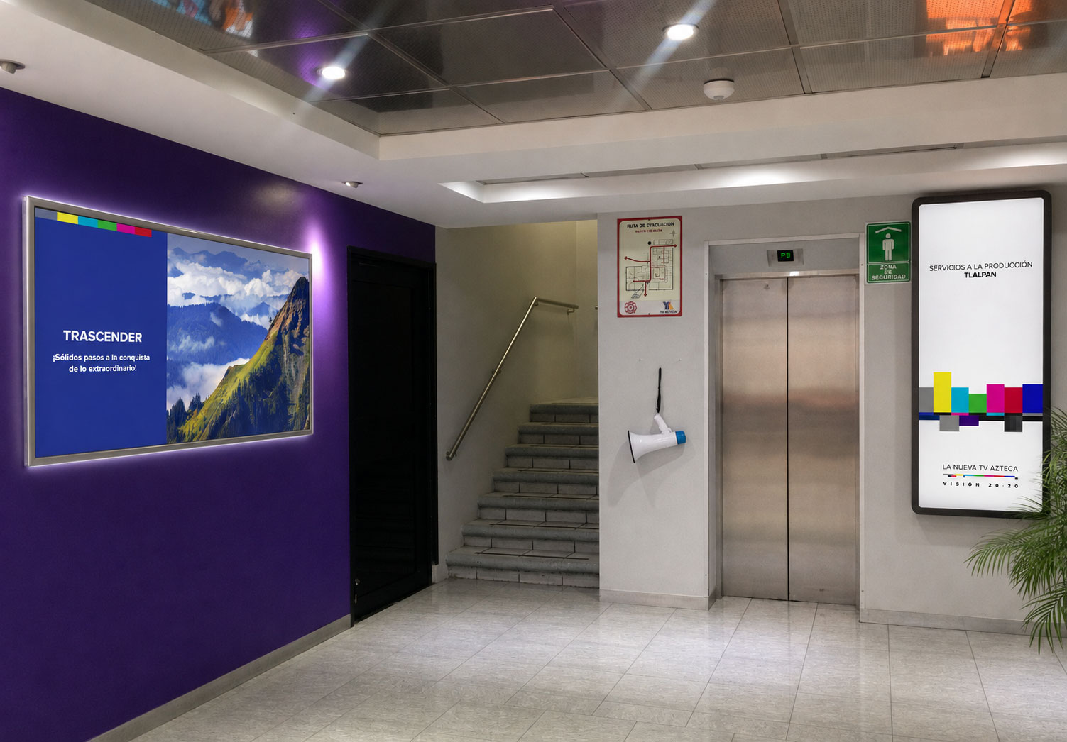 Pasillo con muro morado, marco de acrílico con el mensaje "Trascender" y pantalla vertical con la barra de colores de Visión 20·20