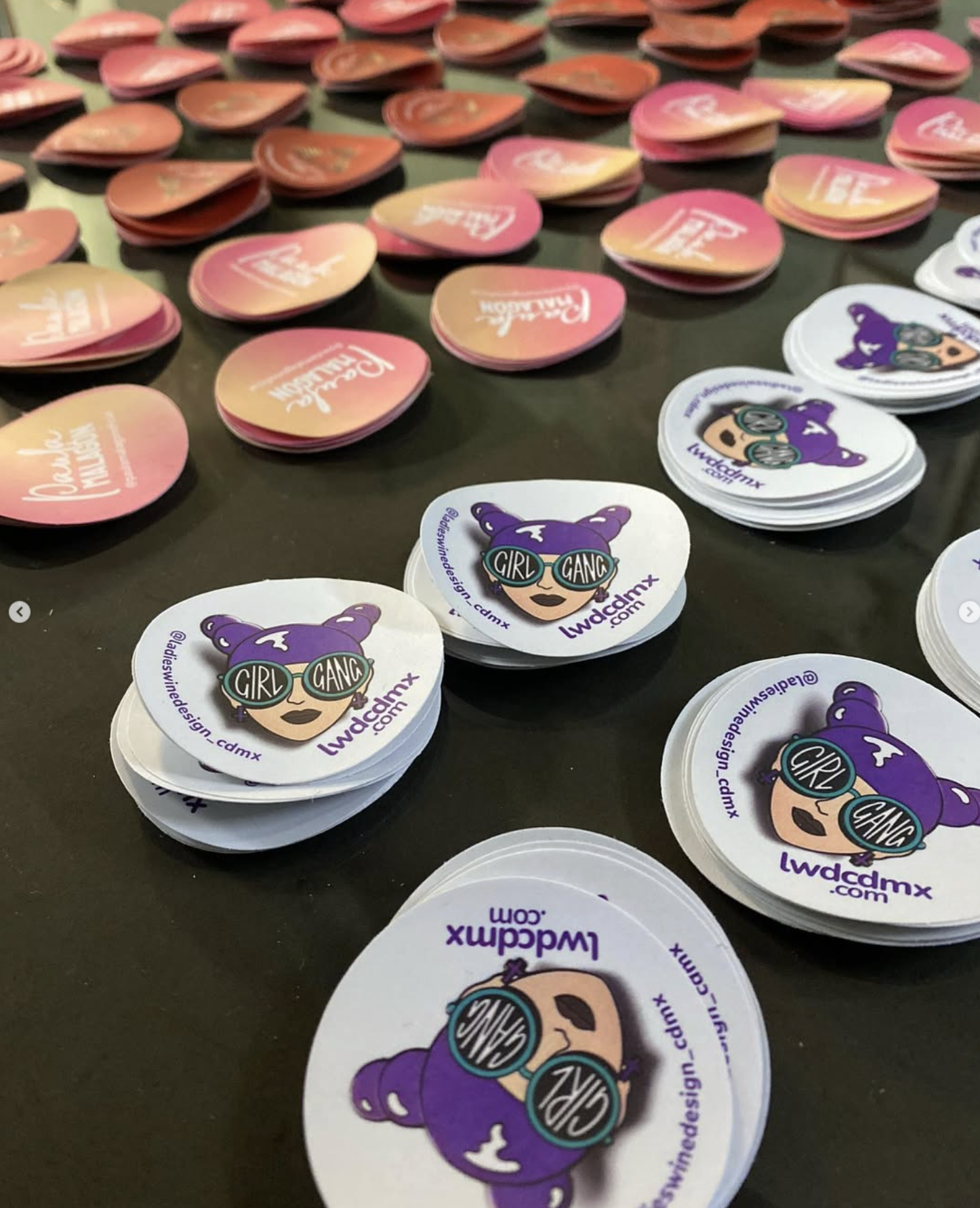 Stickers redondos rosas y blancos del capítulo de Ladies, Wine & Design en la Ciudad de México con un personaje morado «Girl Gang» con lentes de sol