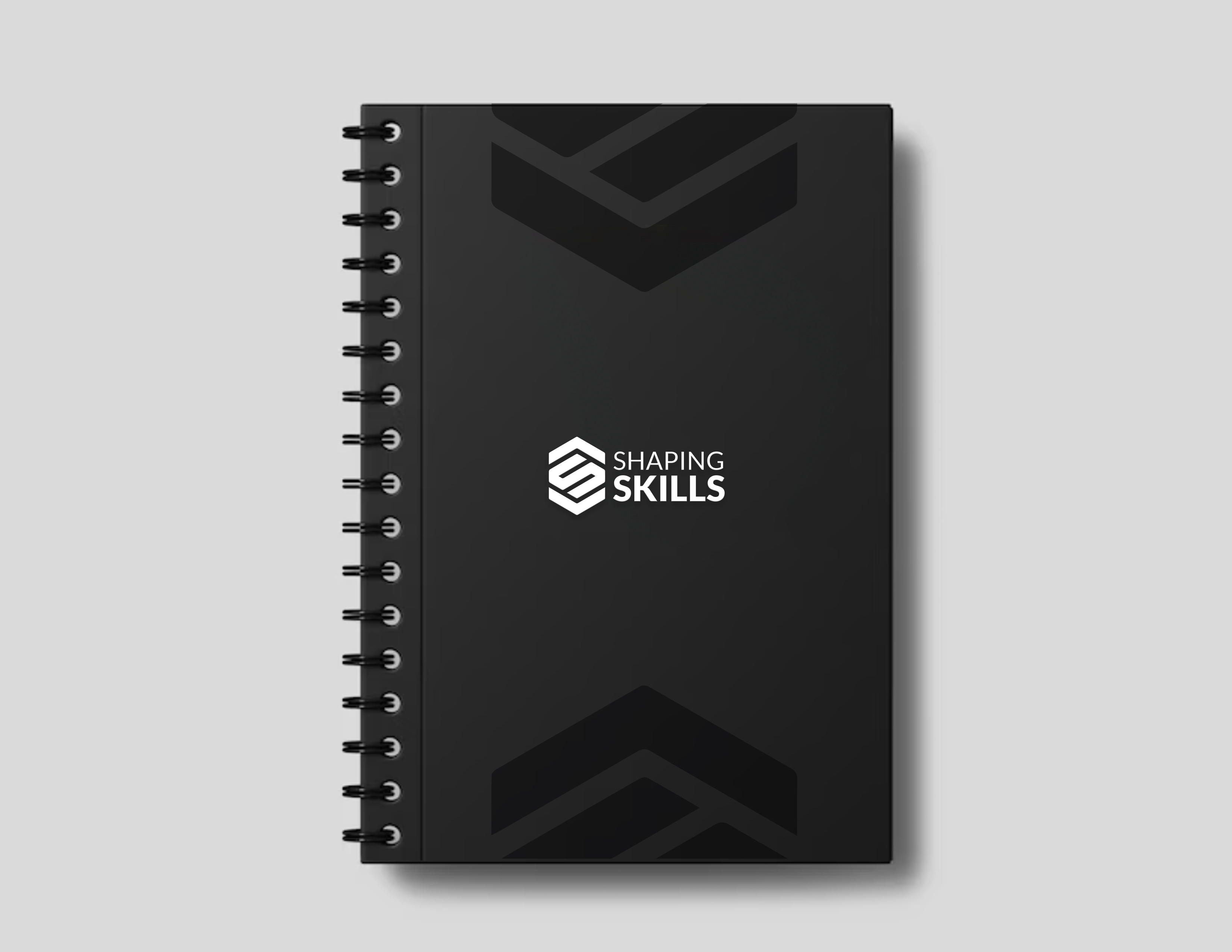 Libreta negra de espiral con el logotipo de Shaping Skills en la portada