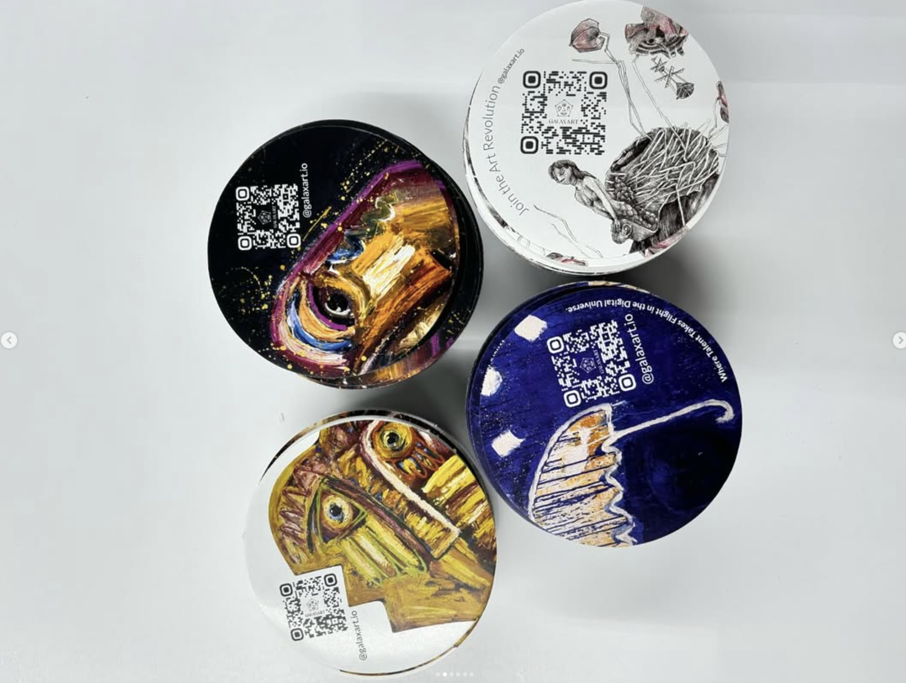Cuatro latas redondas con obras pintadas de colores y códigos QR, vistas desde arriba