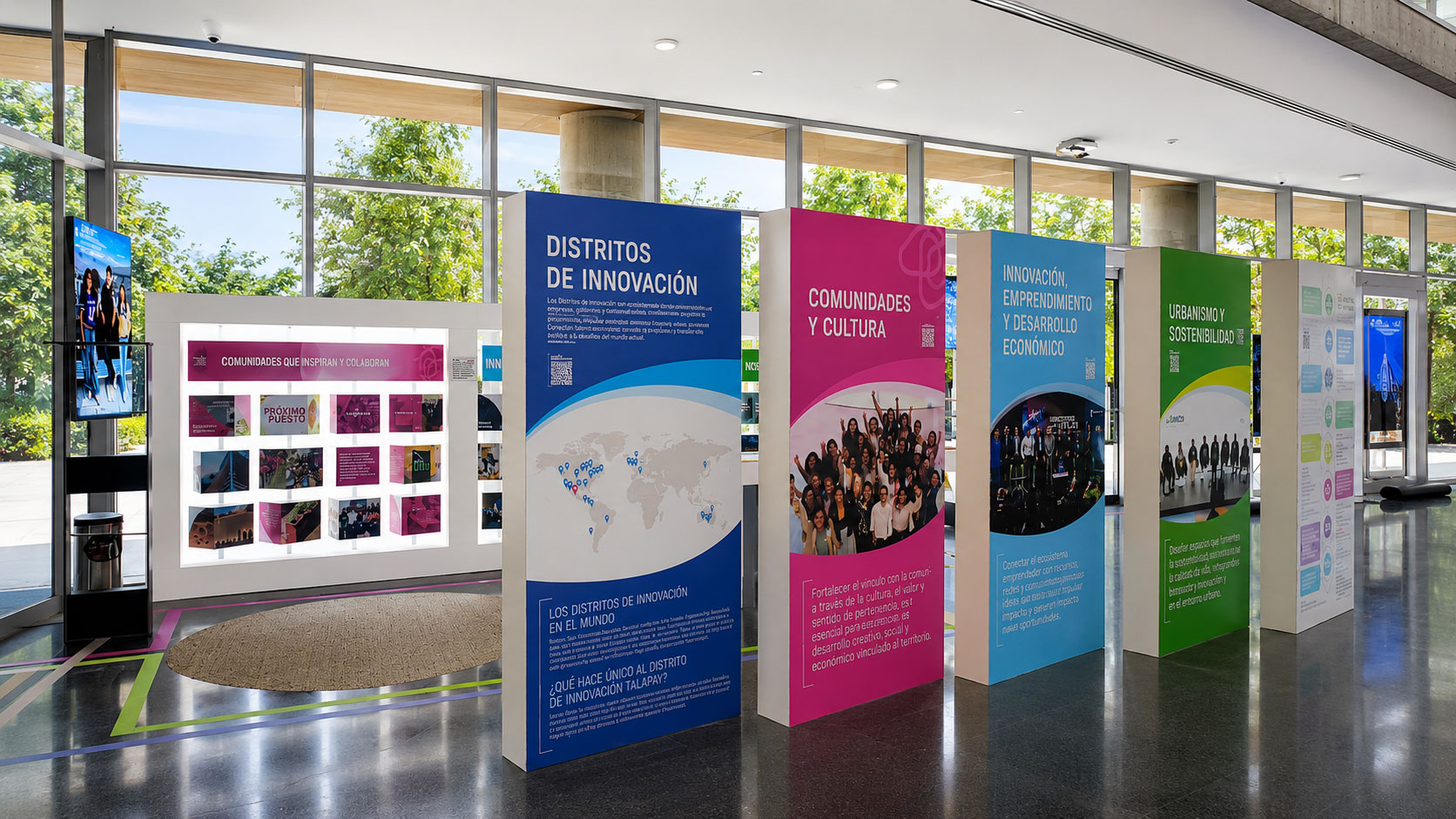 Paneles verticales de colores "Distritos de Innovación", "Comunidades y Cultura" e "Innovación, emprendimiento y desarrollo económico" en el vestíbulo